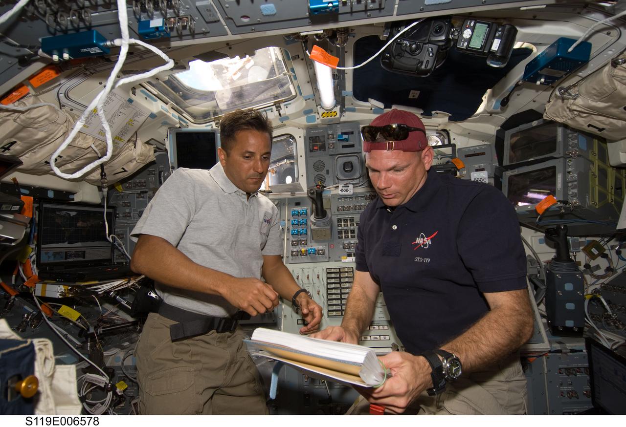 S119-E-006578 (18 March 2009) --- Astronauts Tony Antonelli (right), STS-119 pilot, and Joseph Acaba, mission specialist, look over a procedures checklist on the aft flight deck of Space Shuttle Discovery while docked with the International Space Station.
