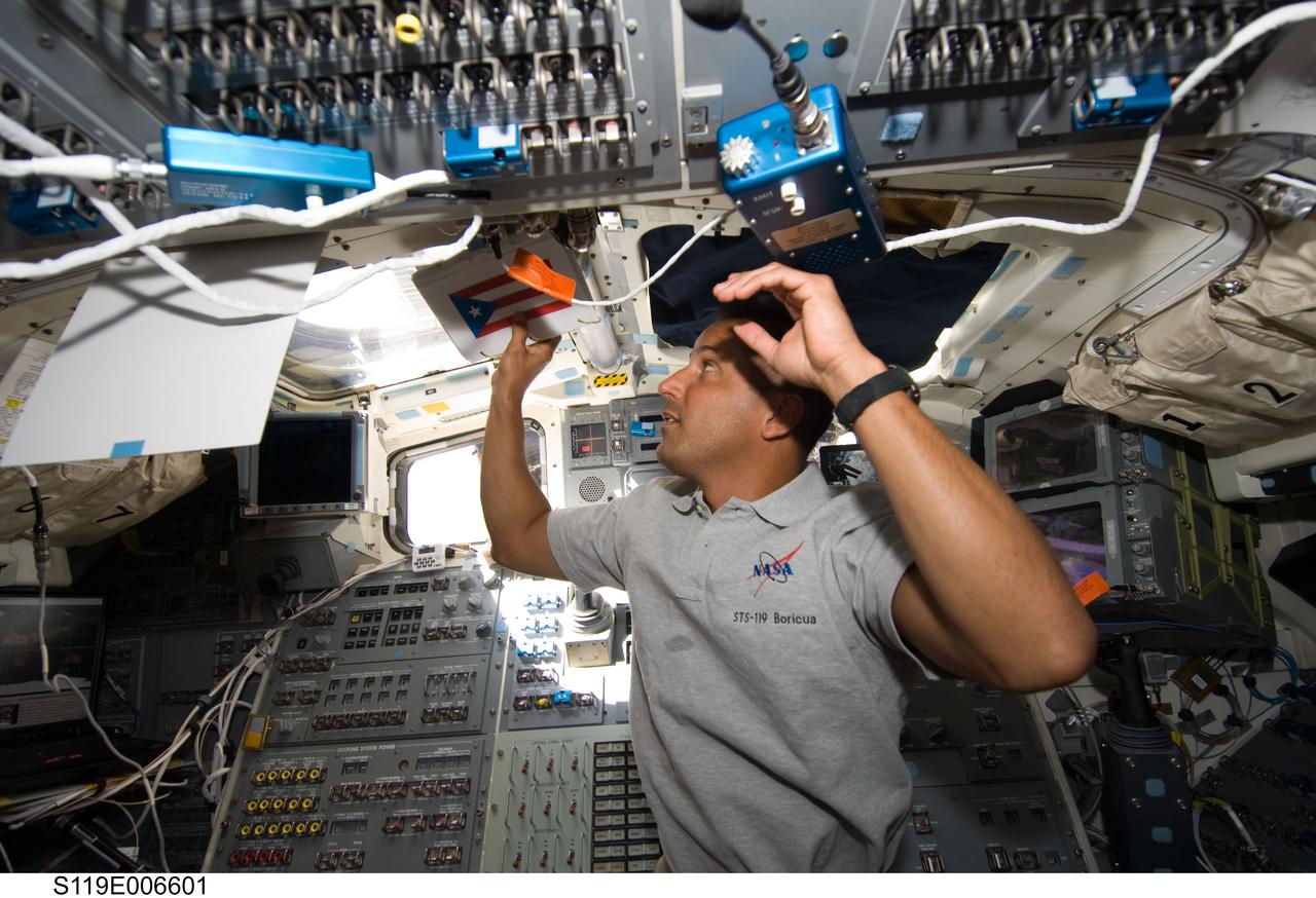 S119-E-006601 (18 March 2009) --- Astronaut Joseph Acaba, STS-119 mission specialist, looks out an overhead window on the aft flight deck of Space Shuttle Discovery while docked with the International Space Station.