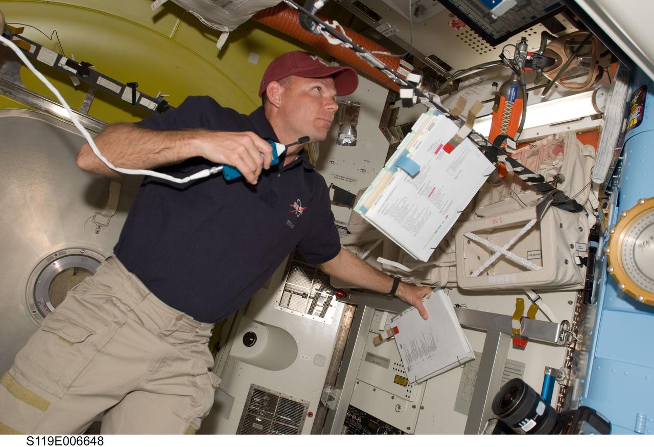 S119-E-006648 (19 March 2009) --- Astronaut Tony Antonelli, STS-119 pilot, uses a communication system in the Quest Airlock of the International Space Station while Space Shuttle Discovery remains docked with the station.