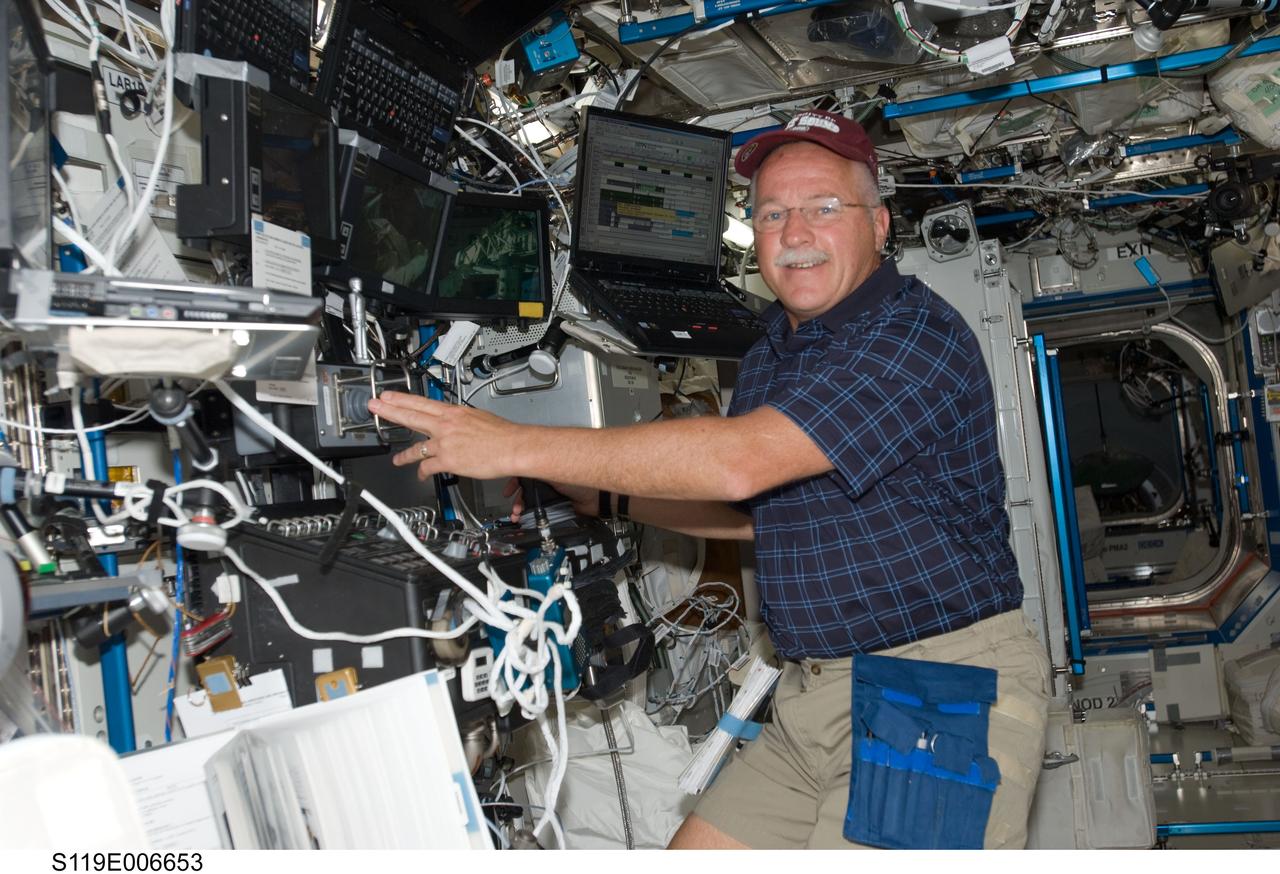 S119-E-006653 (19 March 2009) --- Astronaut John Phillips, STS-119 mission specialist, works the controls of the station's robotic Canadarm2 in the Destiny laboratory of the International Space Station while Space Shuttle Discovery remains docked with the station.