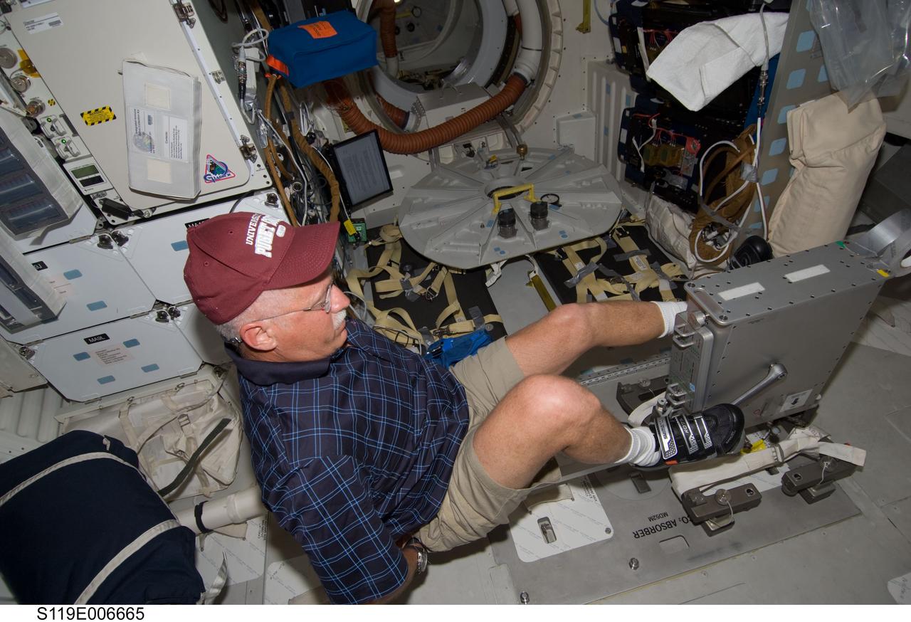 S119-E-006665 (19 March 2009) --- Astronaut John Phillips, STS-119 mission specialist, exercises on a bicycle ergometer on the middeck of Space Shuttle Discovery while docked with the International Space Station.