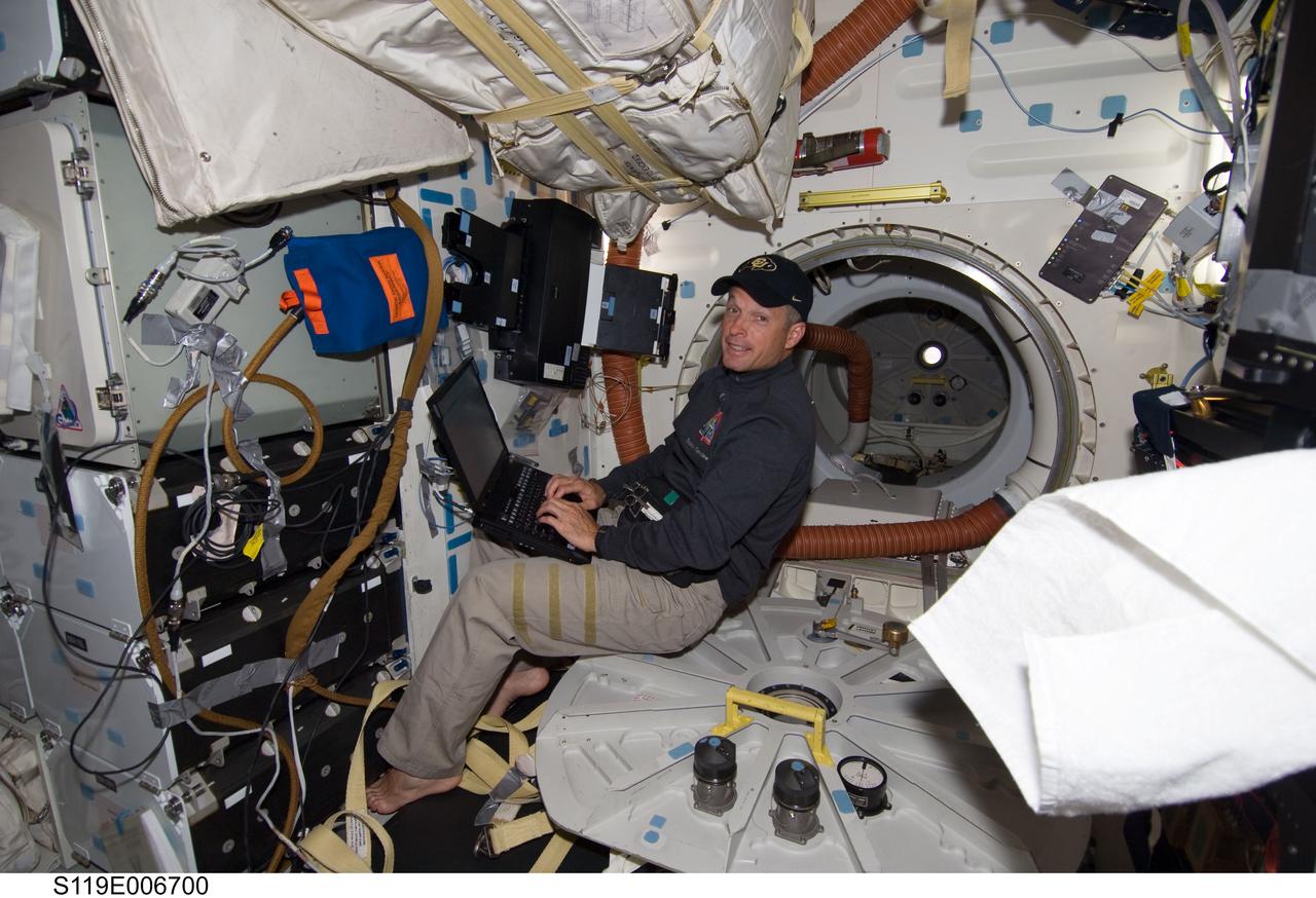 S119-E-006700 (20 March 2009) --- Astronaut Steve Swanson, STS-119 mission specialist, uses a computer onboard the Space Shuttle Discovery during flight day six activities, while the orbiter and the International Space Station are docked in Earth orbit. Swanson performed a spacewalk on March 19, the third of his career, and he prepares for his career's fourth and this mission's second spacewalk on March 21.