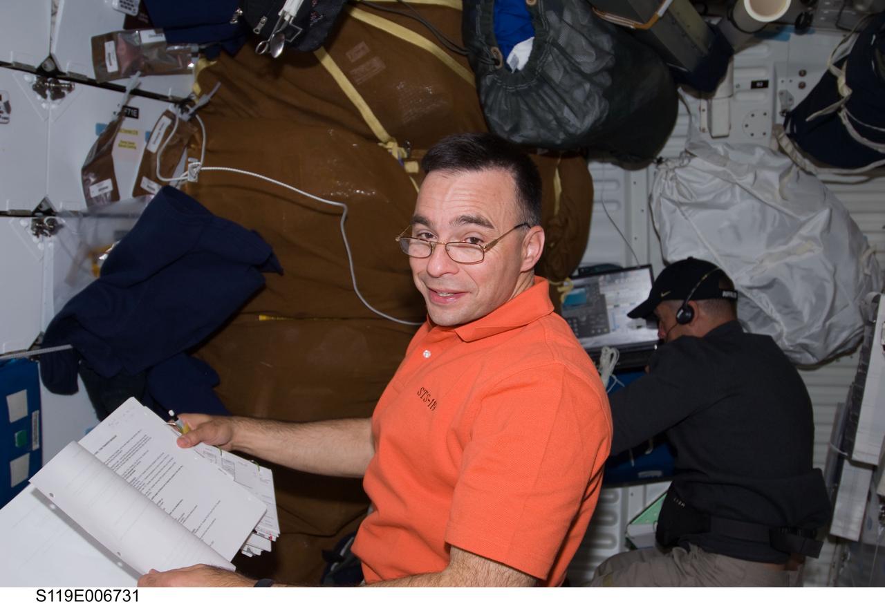 S119-E-006731 (20 March 2009) --- Astronaut Lee Archambault, STS-119 commander, checks out  stored gear on the mid deck of the Space Shuttle Discovery during flight day six activities.