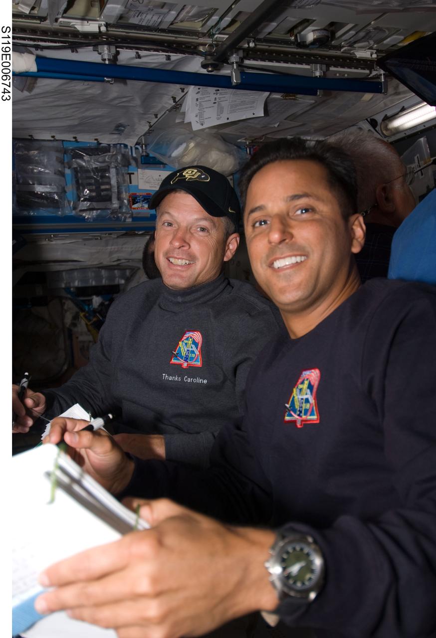 S119-E-006743 (20 March 2009) --- On the eve of a planned shared spacewalk, astronauts Steve  Swanson (left)  and Joseph Acaba, both STS-119 mission specialists, have a meeting in the Joint Airlock aboard the International Space Station, while linked to the Space Shuttle Discovery.