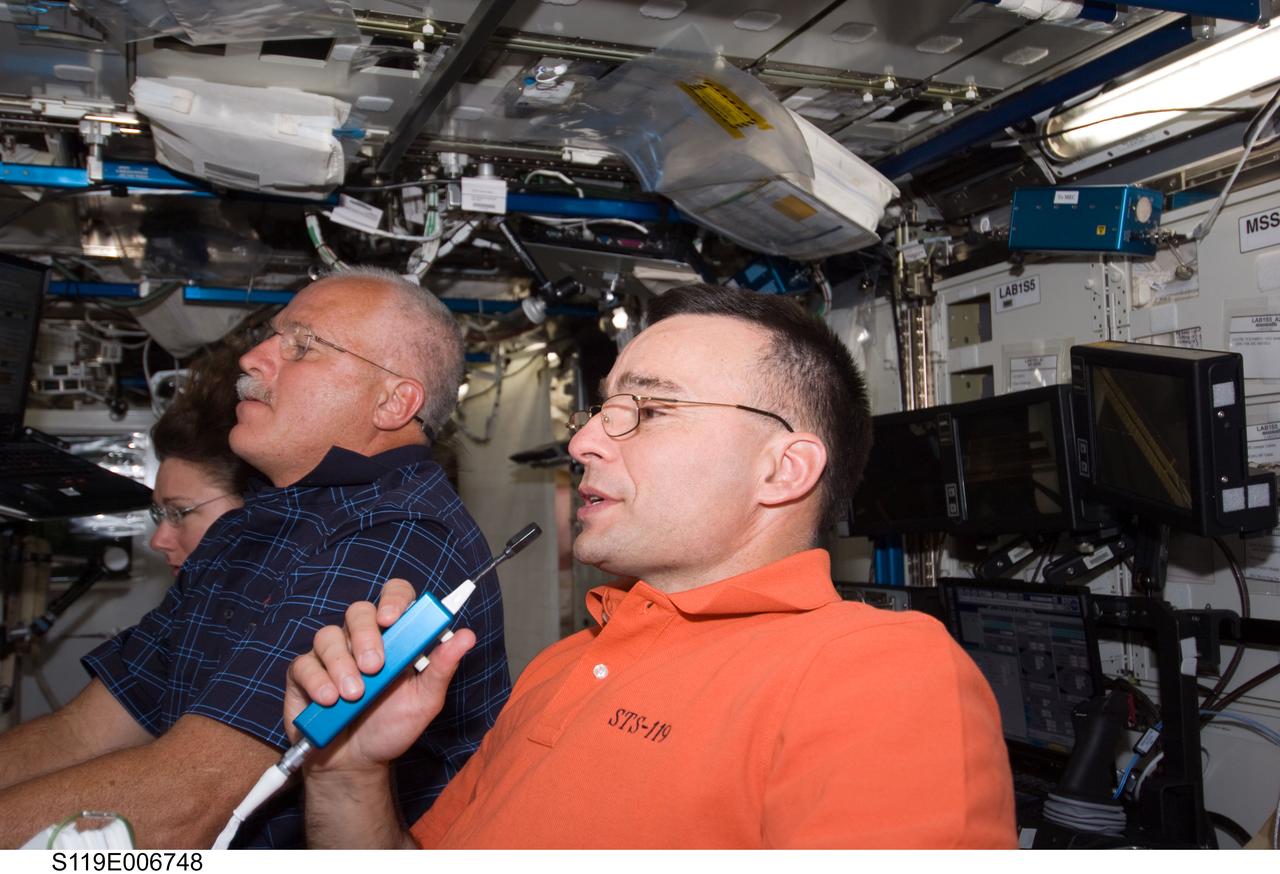 S119-E-006748 (20 March 2009) --- Astronauts Lee Archambault, (foreground), STS-119 commander, John Phillips and Sandra Magnus, both mission specialists, are pictured at the robotic workstation in Destiny or the U.S. laboratory. Magnus is winding down a lengthy tour in space aboard the orbiting outpost, and she will return to Earth with the Discovery crew.