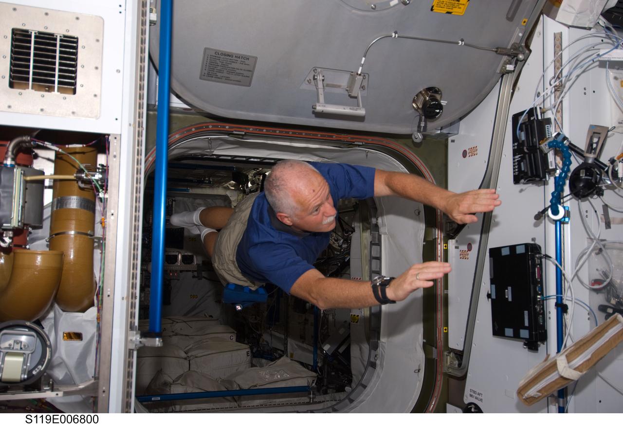 S119-E-006800 (20 March 2009) --- Astronaut John Phillips is about to exit the European Space Agency's Columbus module in a manner quite unique to space travelers. The STS-119 mission specialist and the rest of the Discovery crew are joining forces with the Expedition 18 crew for the continuation of the home improvement project aboard the International Space Station.