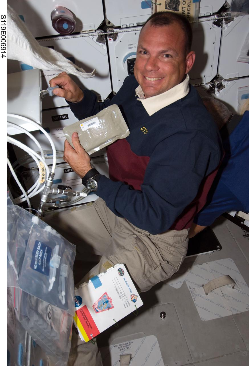 S119-E-006914 (21 March 2009) --- Astronaut Tony Antonelli, STS-119 pilot, prepares to eat a meal near the galley on the middeck of Space Shuttle Discovery while docked with the International Space Station.