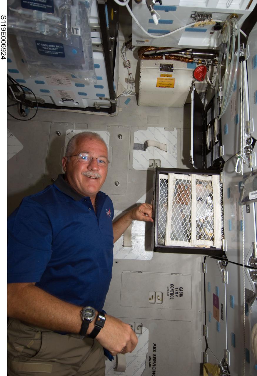 S119-E-006924 (21 March 2009) --- Astronaut John Phillips, STS-119 mission specialist, prepares to eat a meal near the galley on the middeck of Space Shuttle Discovery while docked with the International Space Station.