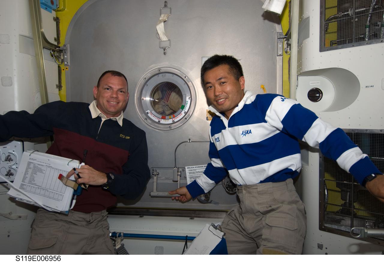 S119-E-006956 (21 March 2009) --- NASA astronaut Tony Antonelli (left), STS-119 pilot; and Japan Aerospace Exploration Agency (JAXA) astronaut Koichi Wakata, Expedition 18 flight engineer, are pictured in the Quest Airlock of the International Space Station while Space Shuttle Discovery remains docked with the station. They are about to open the hatch for Steve Swanson and Joseph Acaba, mission specialists, as they return to the station’s Quest Airlock as the mission’s second session of extravehicular activity (EVA) draws to a close.