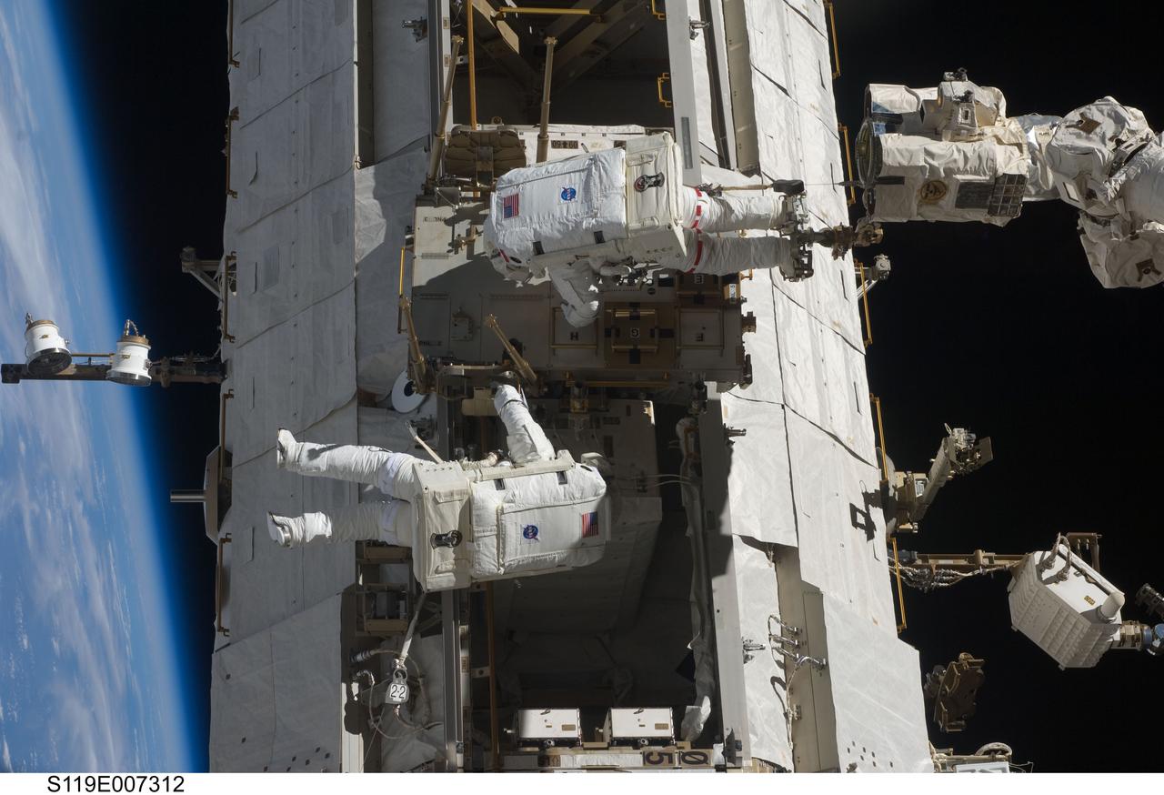 S119-E-007312 (23 March 2009) --- Astronauts Richard Arnold (bottom) and Joseph Acaba, both STS-119 mission specialists, participate in the mission's third scheduled session of extravehicular activity (EVA) as construction and maintenance continue on the International Space Station. During the six-hour, 27-minute spacewalk, Arnold and Acaba helped robotic arm operators relocate the Crew Equipment Translation Aid (CETA) cart from the Port 1 to Starboard 1 truss segment, installed a new coupler on the CETA cart, lubricated snares on the "B" end of the space station's robotic arm and performed a few "get ahead" tasks.