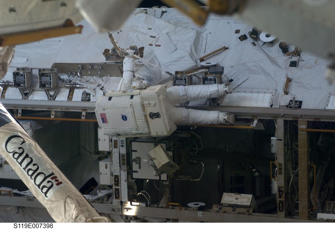 S119-E-007398 (23 March 2009) --- Astronaut Richard Arnold, STS-119 mission specialist, participates in the mission's third scheduled session of extravehicular activity (EVA) as construction and maintenance continue on the International Space Station. During the six-hour, 27-minute spacewalk, Arnold and Joseph Acaba (out of frame), mission specialist, helped robotic arm operators relocate the Crew Equipment Translation Aid (CETA) cart from the Port 1 to Starboard 1 truss segment, installed a new coupler on the CETA cart, lubricated snares on the "B" end of the space station's robotic arm and performed a few "get ahead" tasks.