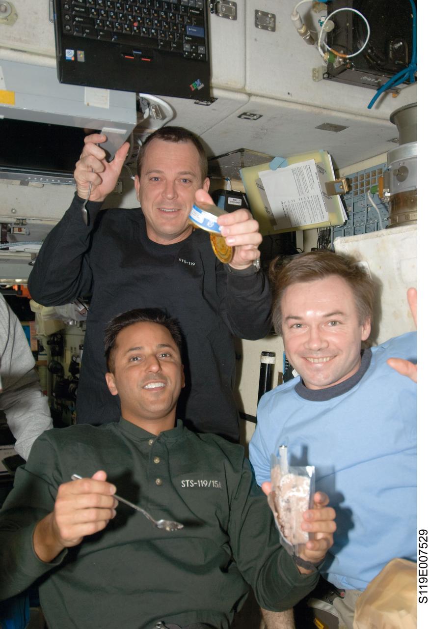 S119-E-007529 (23 March 2009) --- NASA astronauts Joseph Acaba (bottom) and Richard Arnold (top), both STS-119 mission specialists; along with cosmonaut Yury Lonchakov, Expedition 18 flight engineer, share a meal in the Zvezda Service Module of the International Space Station while Space Shuttle Discovery remains docked with the station.