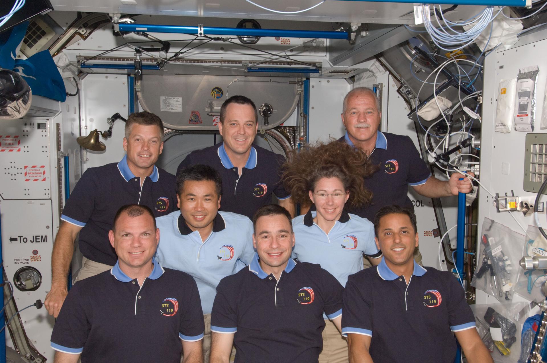 Eight out of the ten crewmembers on the International Space Station pose for a group photo following a joint news conference in the Harmony node while Space Shuttle Discovery remains docked with the station. They are floating in the space station.