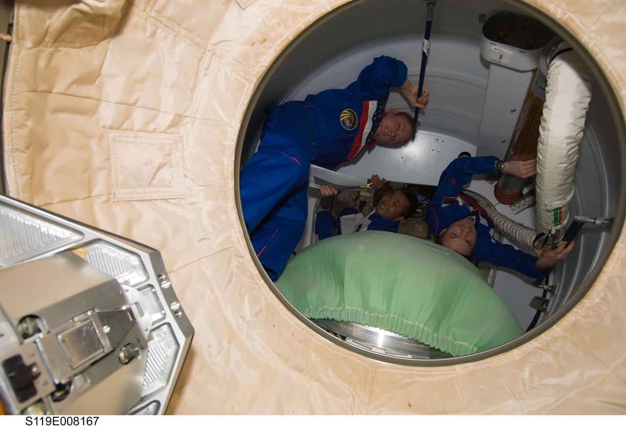 S119-E-008167 (25 March 2009) --- NASA astronaut Michael Fincke (left), Expedition 18 commander; Japan Aerospace Exploration Agency astronaut (JAXA) Koichi Wakata and cosmonaut Yury Lonchakov, both flight engineers, prepare to close the hatch in the Pressurized Mating Adapter (PMA-2) as they bid farewell to the STS-119 crewmembers prior to Space Shuttle Discovery undocking from the International Space Station.