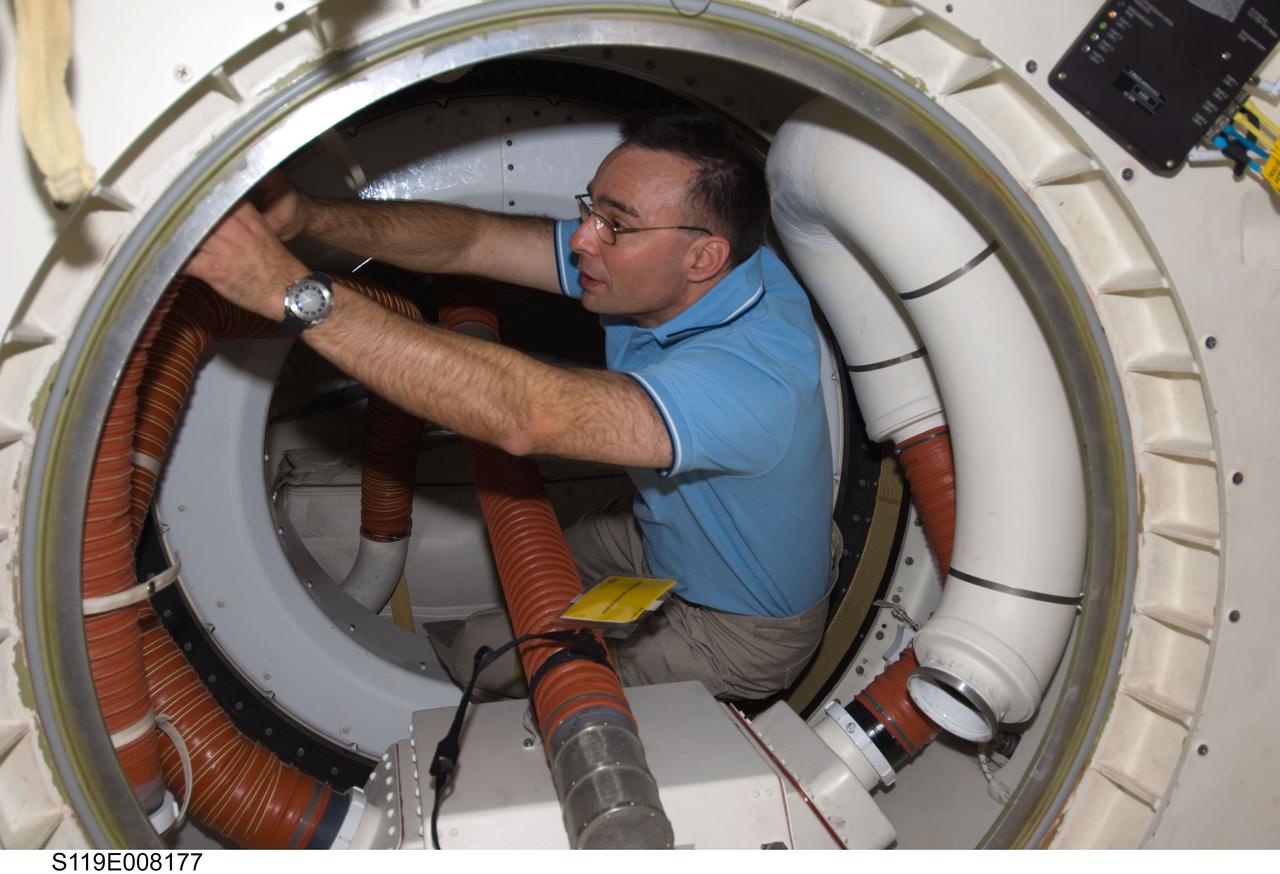 S119-E-008177 (25 March 2009) --- Astronaut Lee Archambault, STS-119 commander, works in a hatch between Space Shuttle Discovery and the International Space Station during flight day 11 activities.
