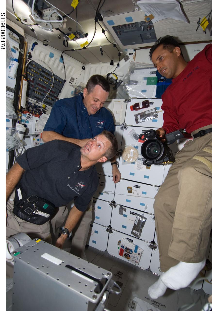 S119-E-008178 (25 March 2009) --- Astronauts Steve Swanson (bottom left), Richard Arnold and Joseph Acaba (right), all STS-119 mission specialists, are pictured on the middeck of Space Shuttle Discovery during flight day 11 activities.