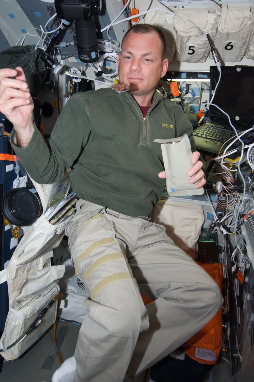 S119-E-008453 (25 March 2009) --- Astronaut Tony Antonelli, STS-119 pilot, watches a spoonful of food float freely while eating a meal on the flight deck of Space Shuttle Discovery.