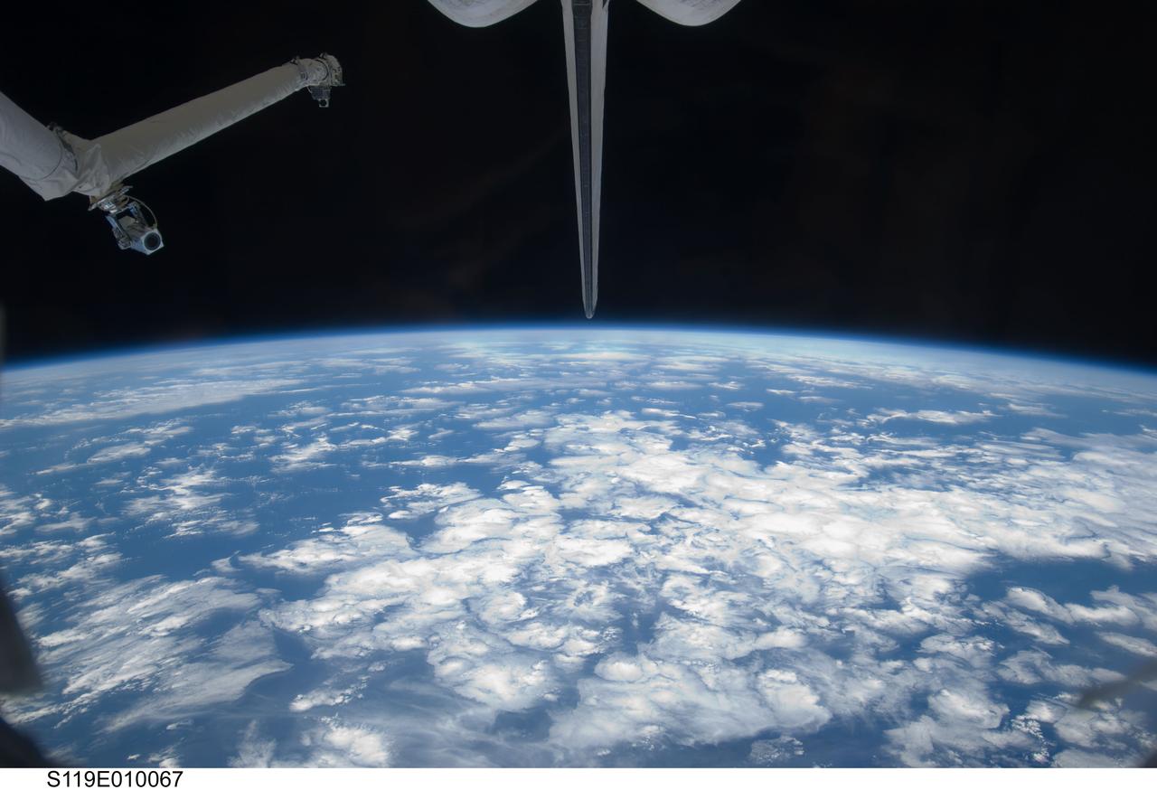 S119-E-010067 (26 March 2009) --- Backdropped by a blue and white Earth and the blackness of space, a portion of Space Shuttle Discovery's Remote Manipulator System (RMS), vertical stabilizer and orbital maneuvering system (OMS) pods are featured in this image photographed by a STS-119 crewmember during flight day 12 activities.