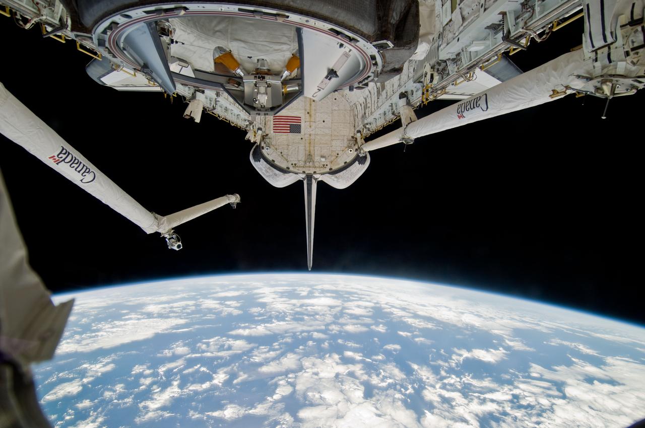 S119-E-010071 (26 March 2009) --- Backdropped by a blue and white Earth and the blackness of space, Space Shuttle Discovery's docking mechanism (top foreground), payload bay, Remote Manipulator System Orbiter Boom Sensor System (RMS/OBSS), vertical stabilizer and orbital maneuvering system (OMS) pods are featured in this image photographed by a STS-119 crewmember during flight day 12 activities.