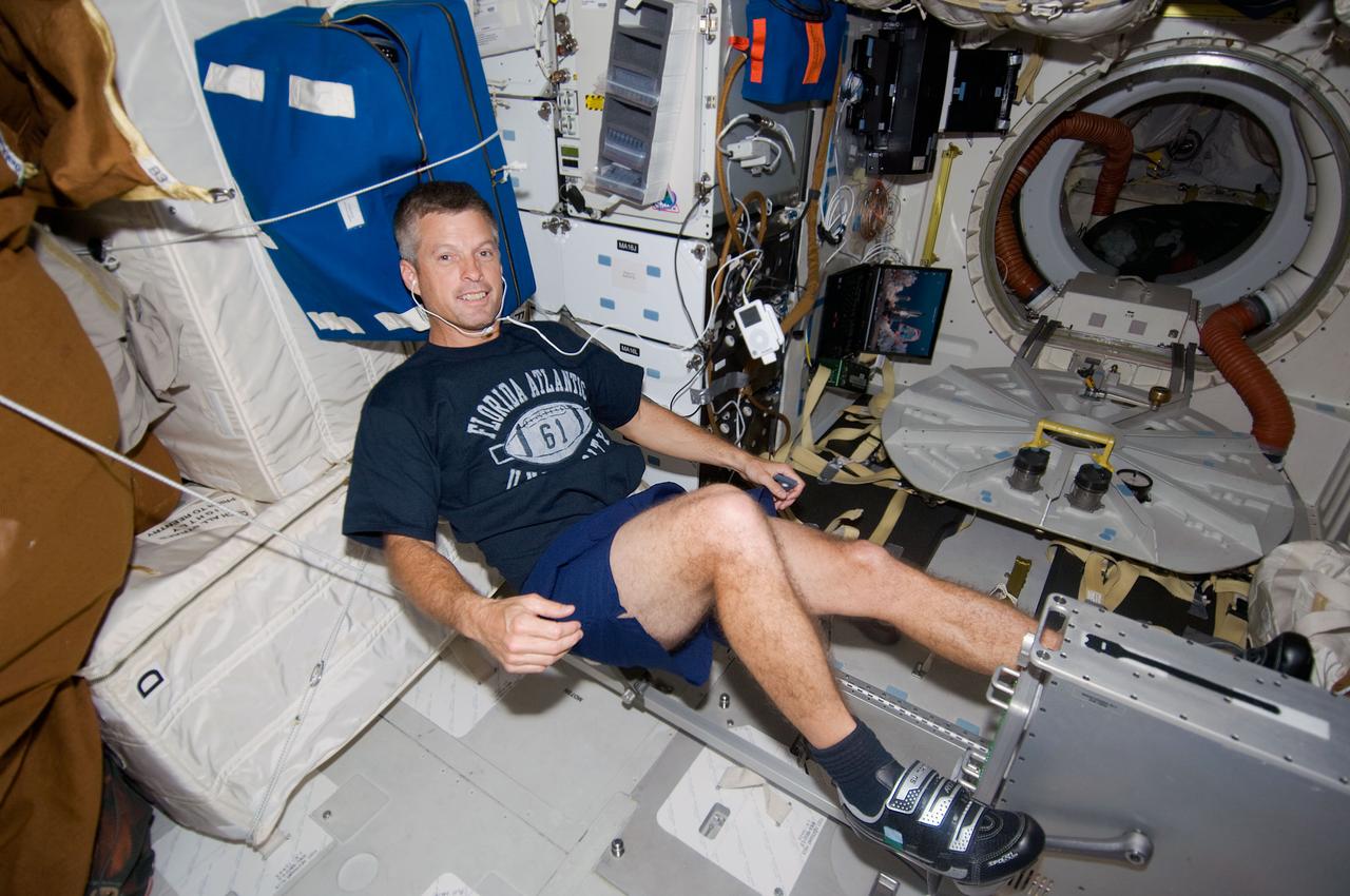 S119-E-010204 (26 March 2009) --- Astronaut Steve Swanson, STS-119 mission specialist, exercises on a bicycle ergometer on the middeck of Space Shuttle Discovery.
