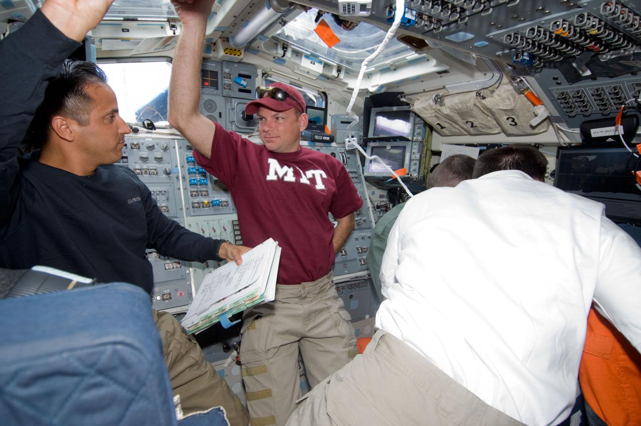 S119-E-010747 (26 March 2009) --- Astronauts Tony Antonelli (center), STS-119 pilot; Joseph Acaba, mission specialist; and Lee Archambault (back to camera), commander, are pictured on the aft flight deck of Space Shuttle Discovery during flight day 12 activities.