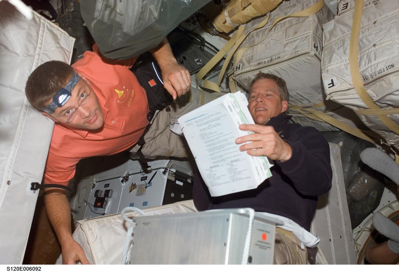S120-E-006092 (24 Oct. 2007) --- Astronauts Doug Wheelock (left) and Scott Parazynski, both STS-120 mission specialists, work among stowage bags on the middeck of Space Shuttle Discovery during flight day two activities.