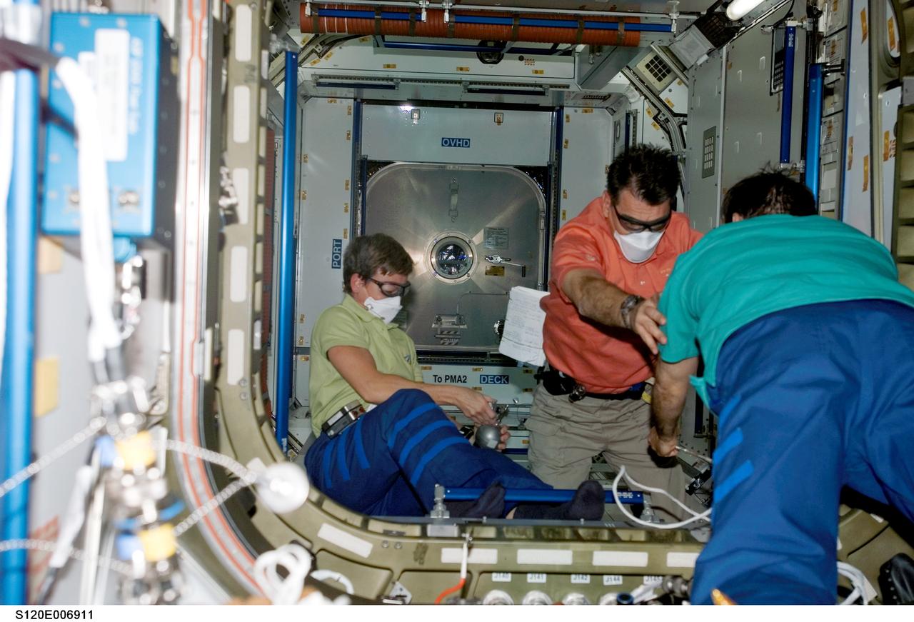 S120-E-006911 (27 Oct. 2007) --- Astronauts Peggy A. Whitson (left), Expedition 16 commander; European Space Agency's (ESA) Paolo Nespoli, STS-120 mission specialist; and cosmonaut Yuri I. Malenchenko, flight engineer representing Russia's Federal Space Agency, work in the Harmony node -- the newest additional to the International Space Station -- while Space Shuttle Discovery is docked with the station.
