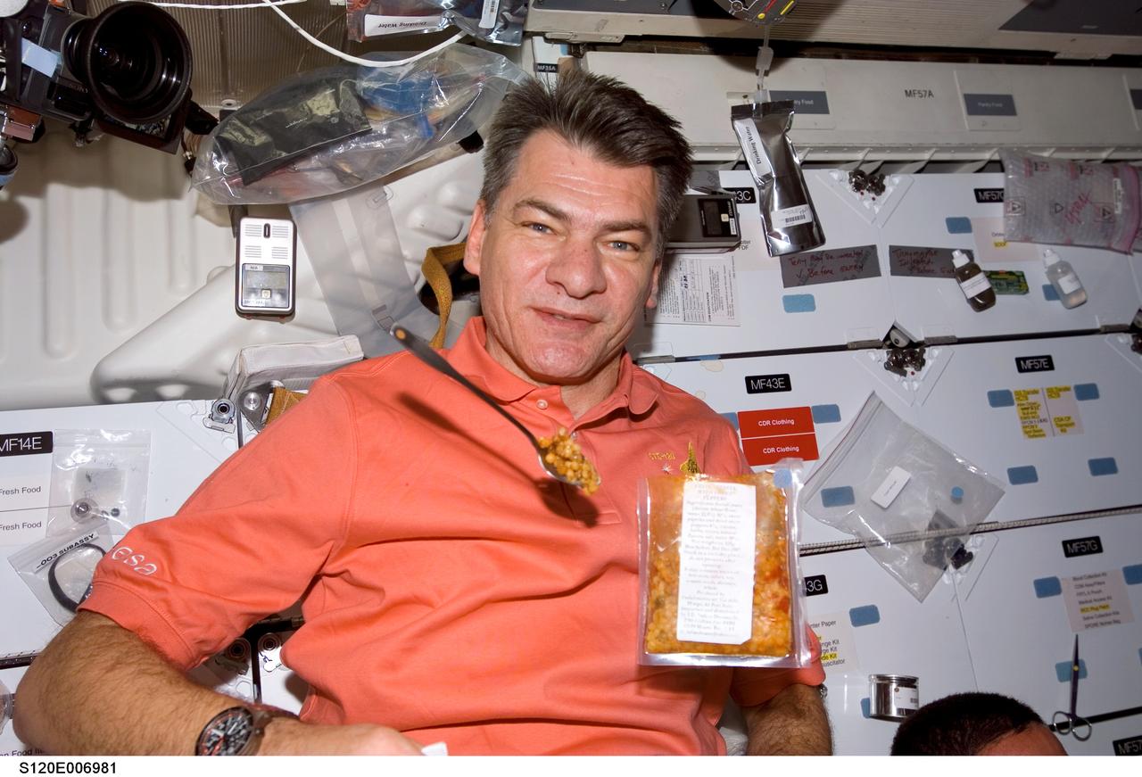 S120-E-006981 (27 Oct. 2007) --- European Space Agency (ESA) astronaut Paolo Nespoli, STS-120 mission specialist, poses for a photo with his meal floating freely nearby on the middeck of Space Shuttle Discovery while docked with the International Space Station.