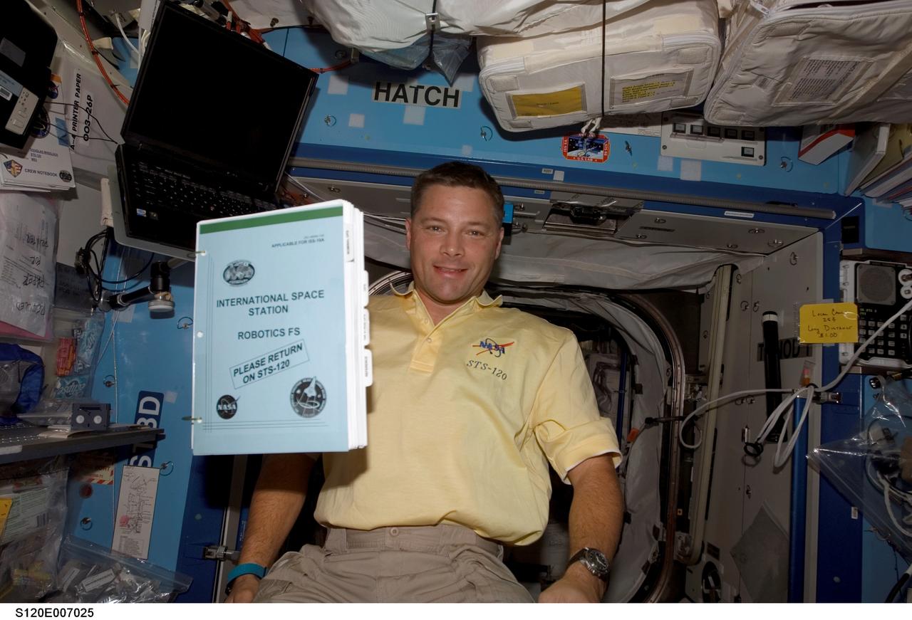 S120-E-007025 (28 Oct. 2007) --- Astronaut Doug Wheelock, STS-120 mission specialist, poses for a photo as a procedures handbook floats freely nearby in the Destiny laboratory of the International Space Station.