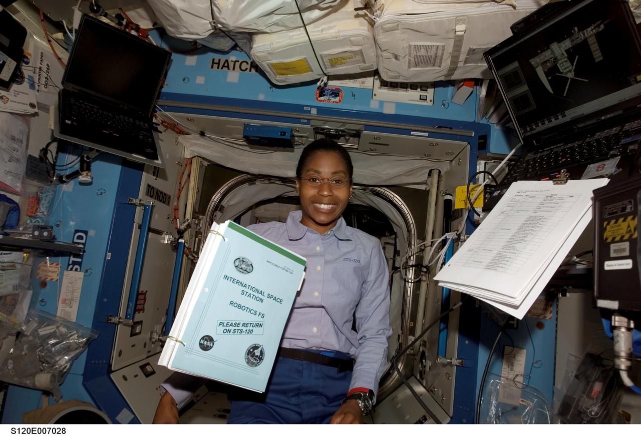 S120-E-007028 (28 Oct. 2007) --- Astronaut Stephanie Wilson, STS-120 mission specialist, poses for a photo as a procedures handbook floats freely nearby in the Destiny laboratory of the International Space Station.