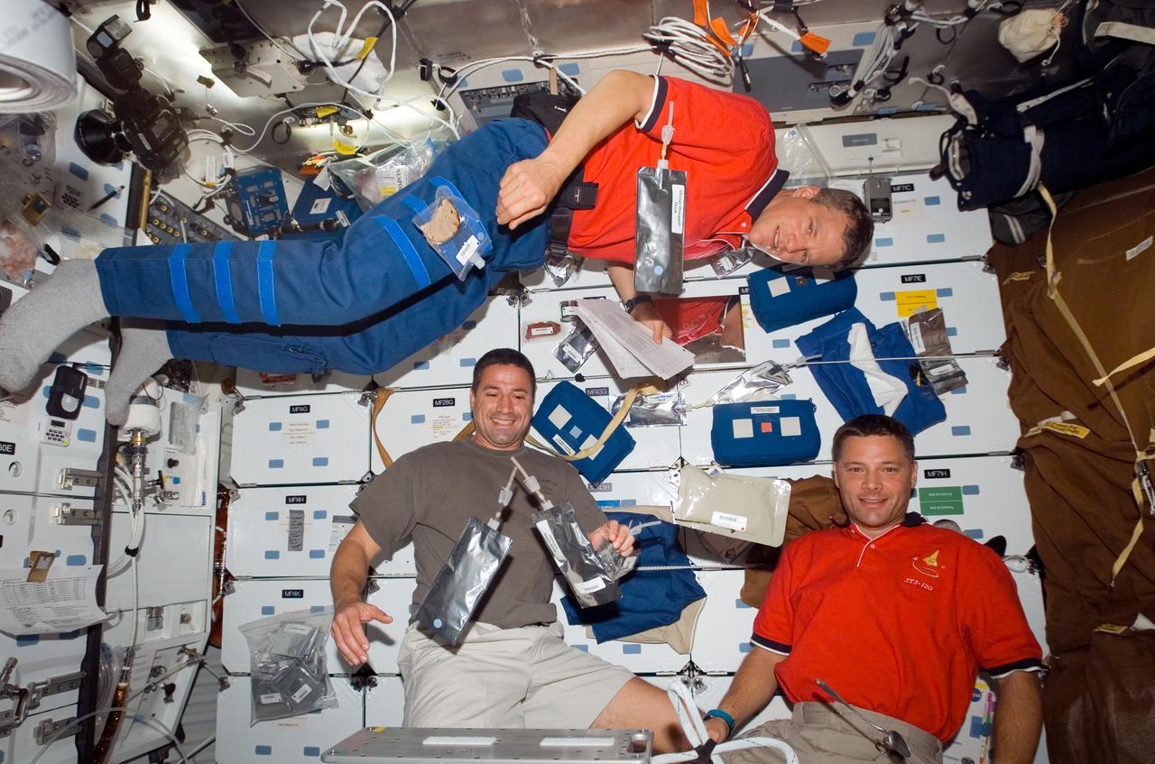 S120-E-007896 (1 Nov. 2007) --- Astronauts Scott Parazynski (top), Doug Wheelock (right), both STS-120 mission specialists; and George Zamka, pilot, share a snack on the middeck of Space Shuttle Discovery while docked with the International Space Station.