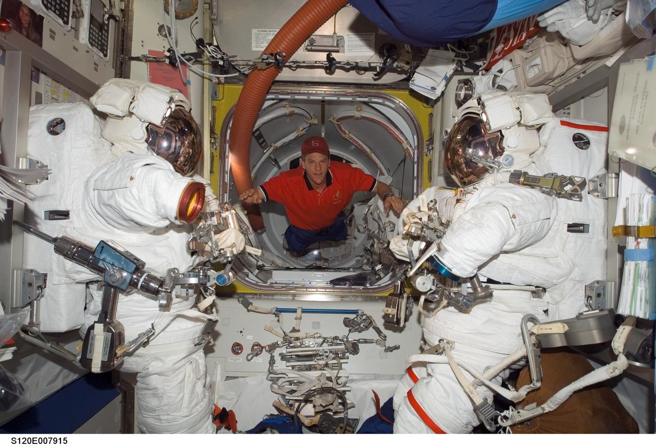 S120-E-007915 (1 Nov. 2007) --- Astronaut Scott Parazynski, STS-120 mission specialist, floats between two Extravehicular Mobility Unit (EMU) spacesuits in the Quest Airlock of the International Space Station while Space Shuttle Discovery is docked with the station.