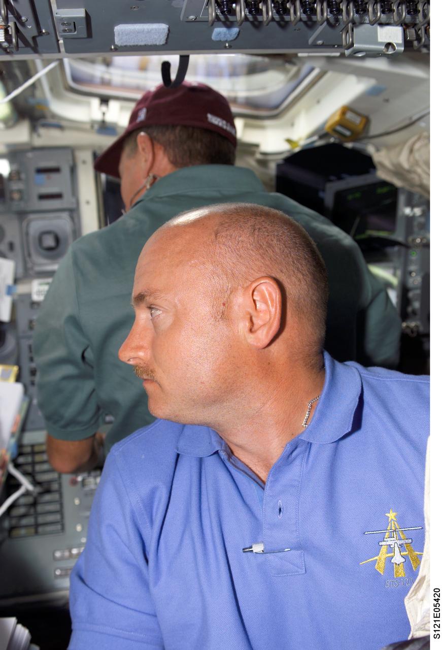 S121-E-05420 (5 July 2006) --- Astronaut Mark E. Kelly, STS-121 pilot, joins his Discovery crewmates on the flight deck as they prepare for the upcoming docking day. Astronaut Michael E. Fossum is seen on the aft flight deck in the background.