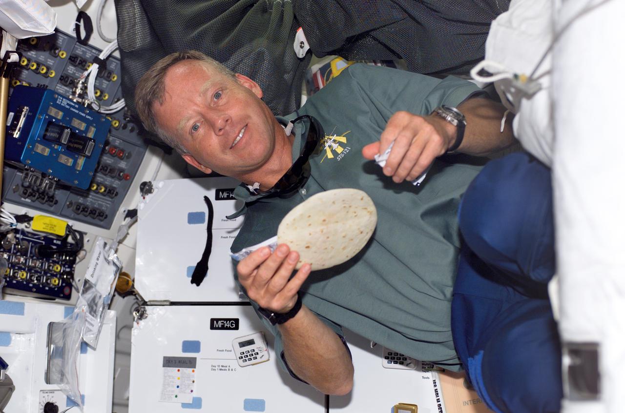 S121-E-05879 (6 July 2006) --- Astronaut Steven W. Lindsey, STS-121 commander, holds a tortilla as he prepares to eat a meal on the middeck of the Space Shuttle Discovery.