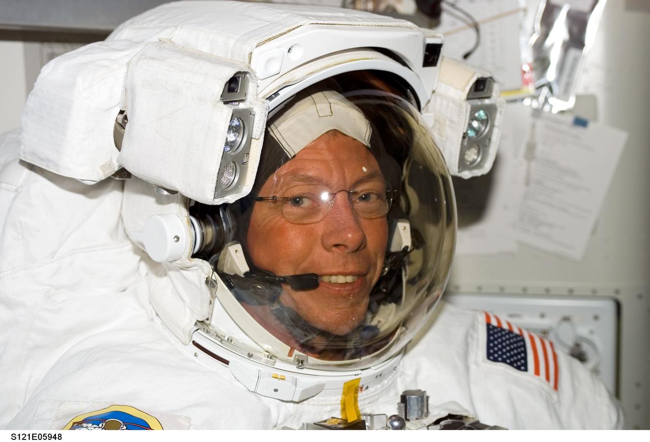 S121-E-05948 (8 July 2006) --- Astronaut Michael E. Fossum, STS-121 mission specialist, attired in his Extravehicular Mobility Unit (EMU) spacesuit, awaits the start of the first scheduled session of extravehicular activity (EVA) in the Quest Airlock of the International Space Station.