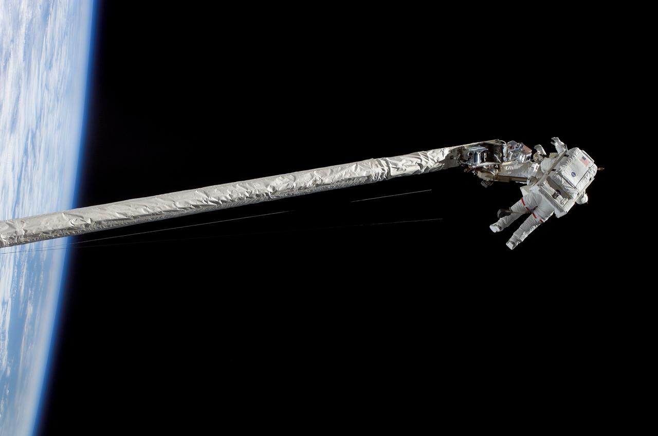 S121-E-06056 (8 July 2006) --- Astronauts Piers J. Sellers (red stripes) and Michael E. Fossum, STS-121 mission specialists, work in tandem on the shuttle's Remote Manipulator System/Orbiter Boom Sensor System (RMS/OBSS) during the mission's first scheduled session of extravehicular activity (EVA).