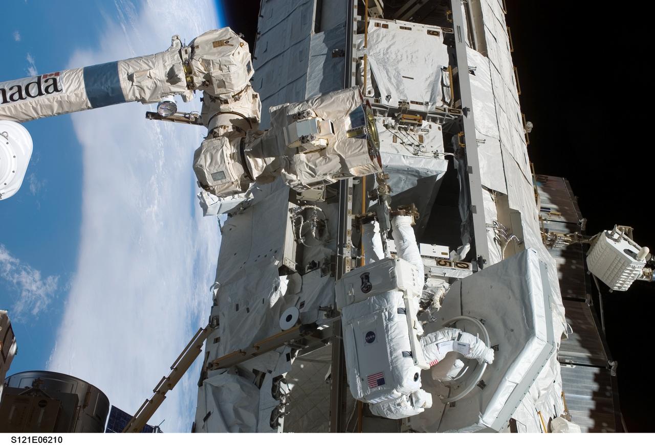 S121-E-06210 (10 July 2006) --- Astronaut Michael E. Fossum, STS-121 mission specialist, removes the trailing umbilical system-reel assembly (TUS-RA) from the S0 truss on the International Space Station during the mission's second session of extravehicular activity (EVA). Fossum is anchored on the mobile foot restraint on the Canadarm2.