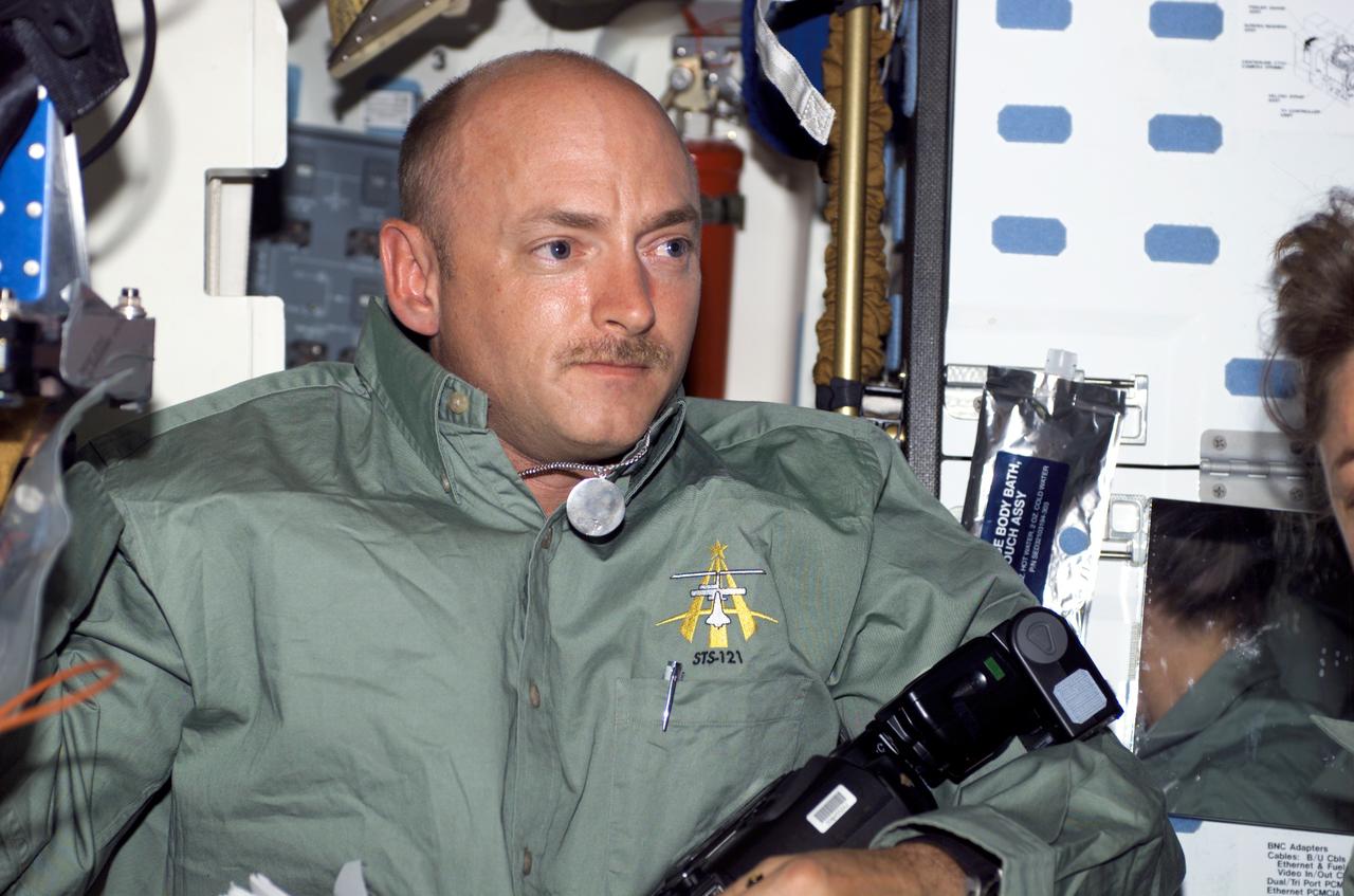 S121-E-06259 (9 July 2006) --- Astronaut Mark E. Kelly, STS-121 pilot, holds a camera on the middeck of the Space Shuttle Discovery while docked with the International Space Station.