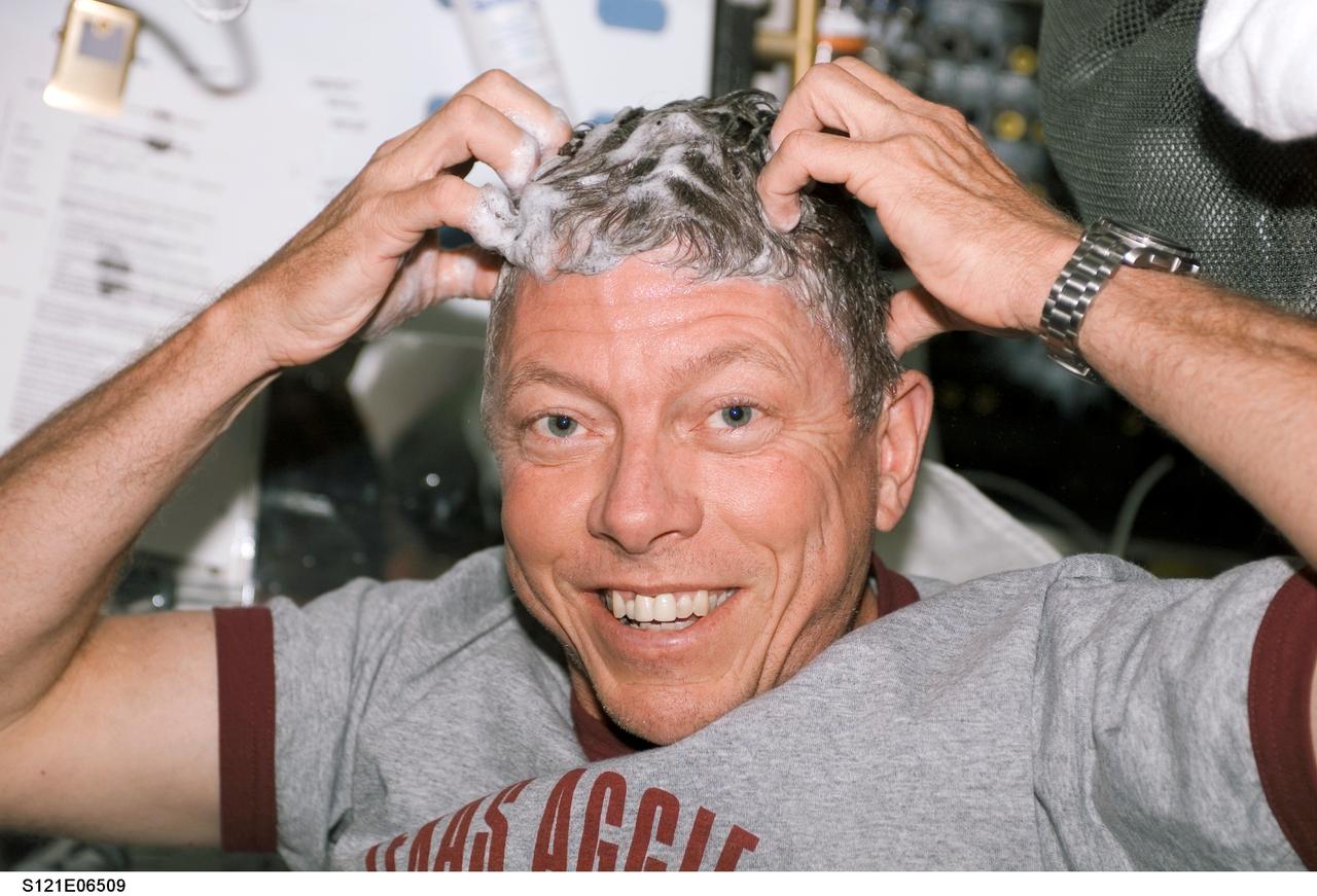 S121-E-06509 (13 July 2006) --- Astronaut Michael E. Fossum, STS-121 mission specialist, washes his hair on the middeck of the Space Shuttle Discovery while docked with the International Space Station.