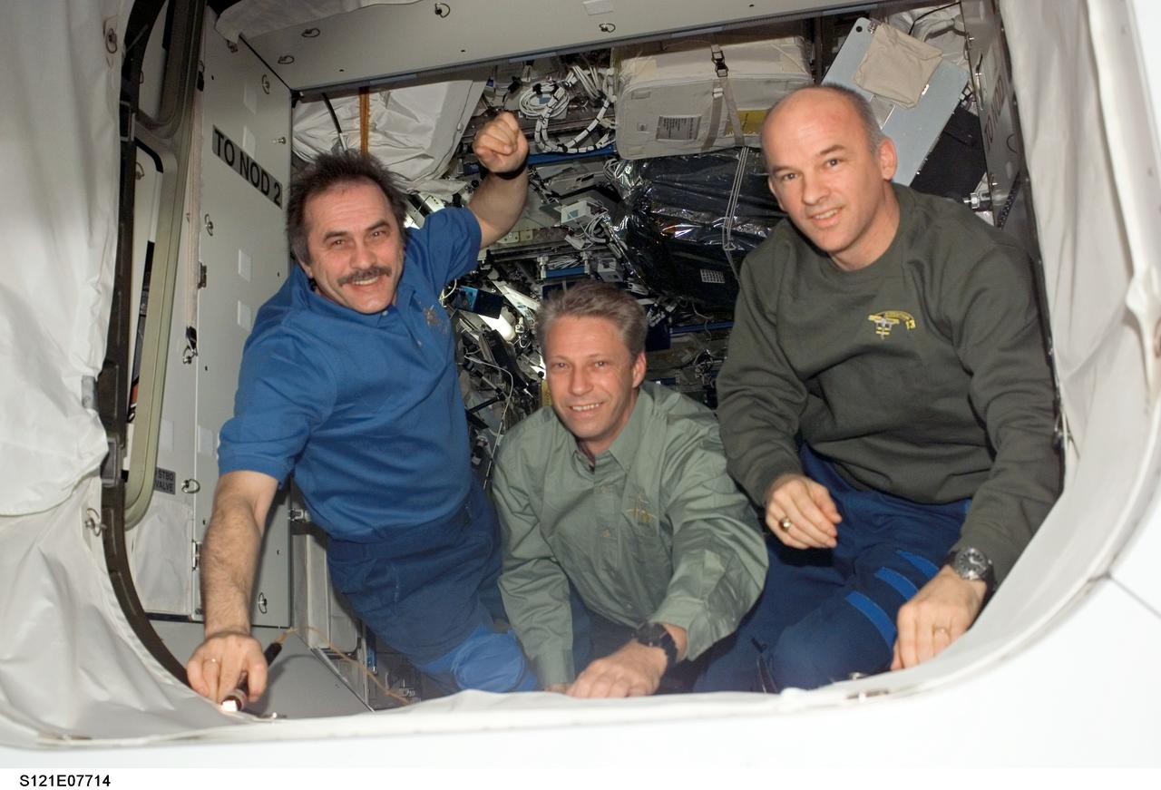 S121-E-07714 (15 July 2006) --- Cosmonaut Pavel V. Vinogradov (left), Expedition 13 commander representing Russia's Federal Space Agency; European Space Agency (ESA) astronaut Thomas Reiter, flight engineer; and astronaut Jeffrey N. Williams, NASA space station science officer and flight engineer, are photographed by the departing STS-121 crew (out of frame) prior to the undocking of Space Shuttle Discovery from the International Space Station. Undocking of the two spacecraft occurred at 5:08 a.m. (CDT) on July 15, 2006.