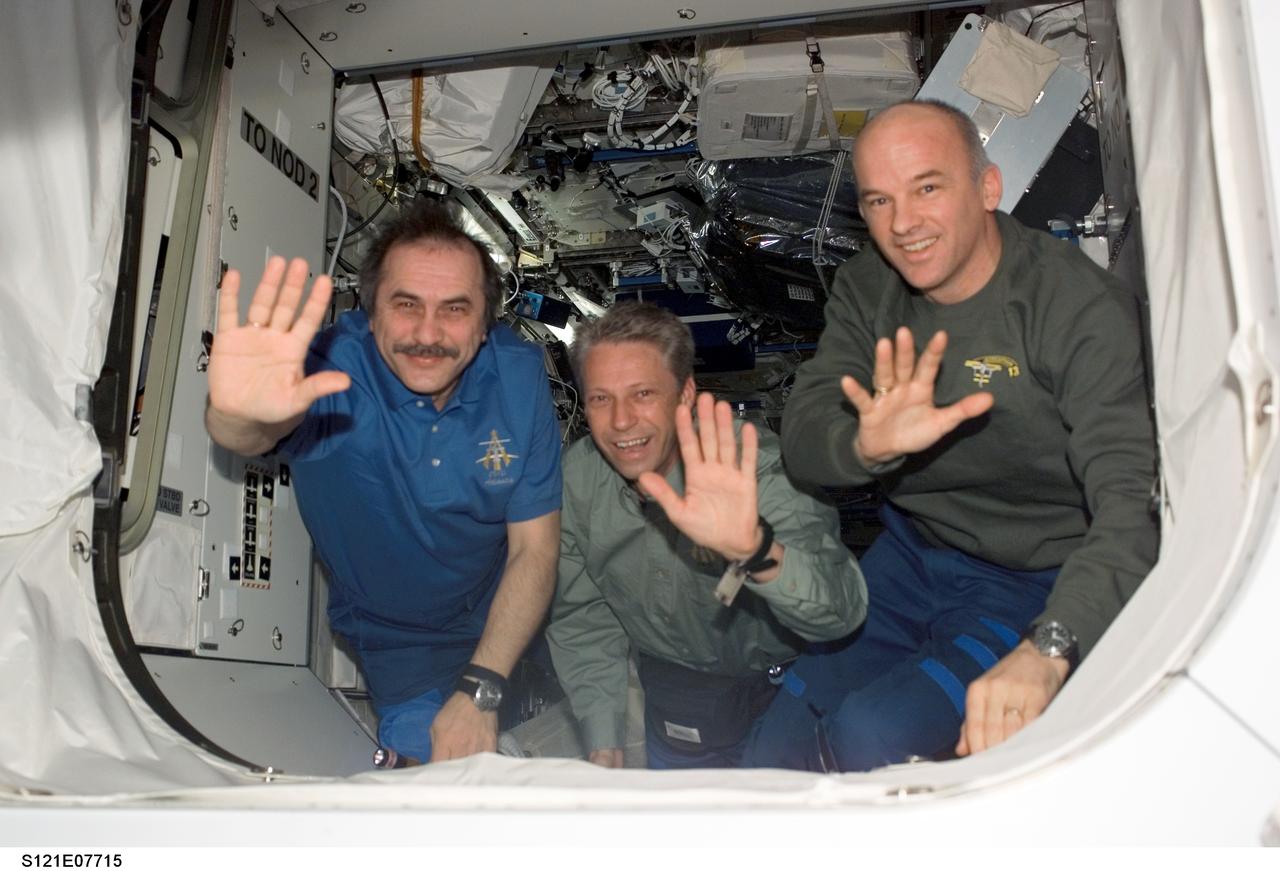 S121-E-07715 (15 July 2006) --- Cosmonaut Pavel V. Vinogradov (left), Expedition 13 commander representing Russia's Federal Space Agency; European Space Agency (ESA) astronaut Thomas Reiter, flight engineer; and astronaut Jeffrey N. Williams, NASA space station science officer and flight engineer, wave to the departing STS-121 crew (out of frame) prior to the undocking of Space Shuttle Discovery from the International Space Station. Undocking of the two spacecraft occurred at 5:08 a.m. (CDT) on July 15, 2006.