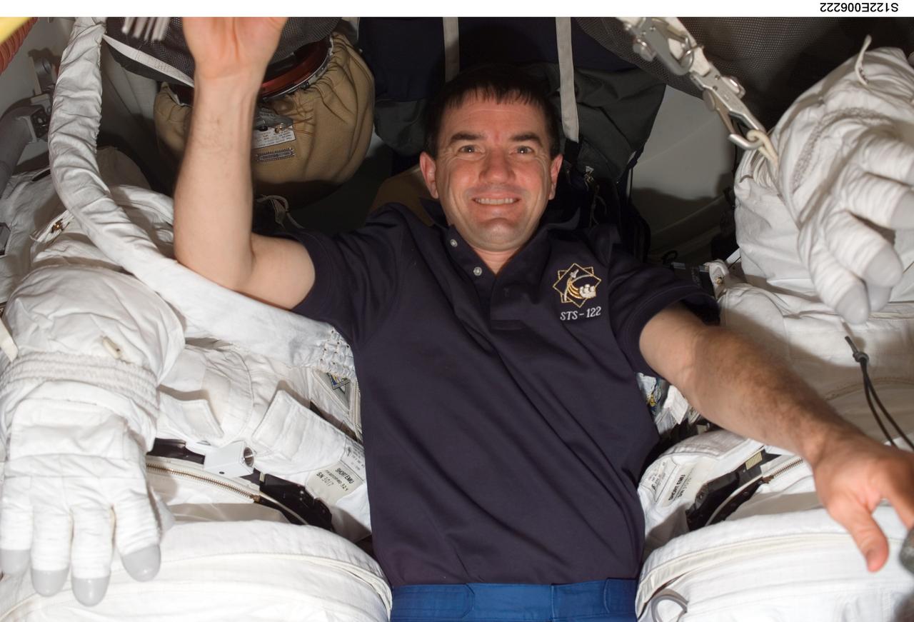 S122-E-006222 (8 Feb. 2008) --- Astronaut Rex Walheim, STS-122 mission specialist, is pictured between two Extravehicular Mobility Unit (EMU) spacesuits on the middeck of Space Shuttle Atlantis during flight day two activities.