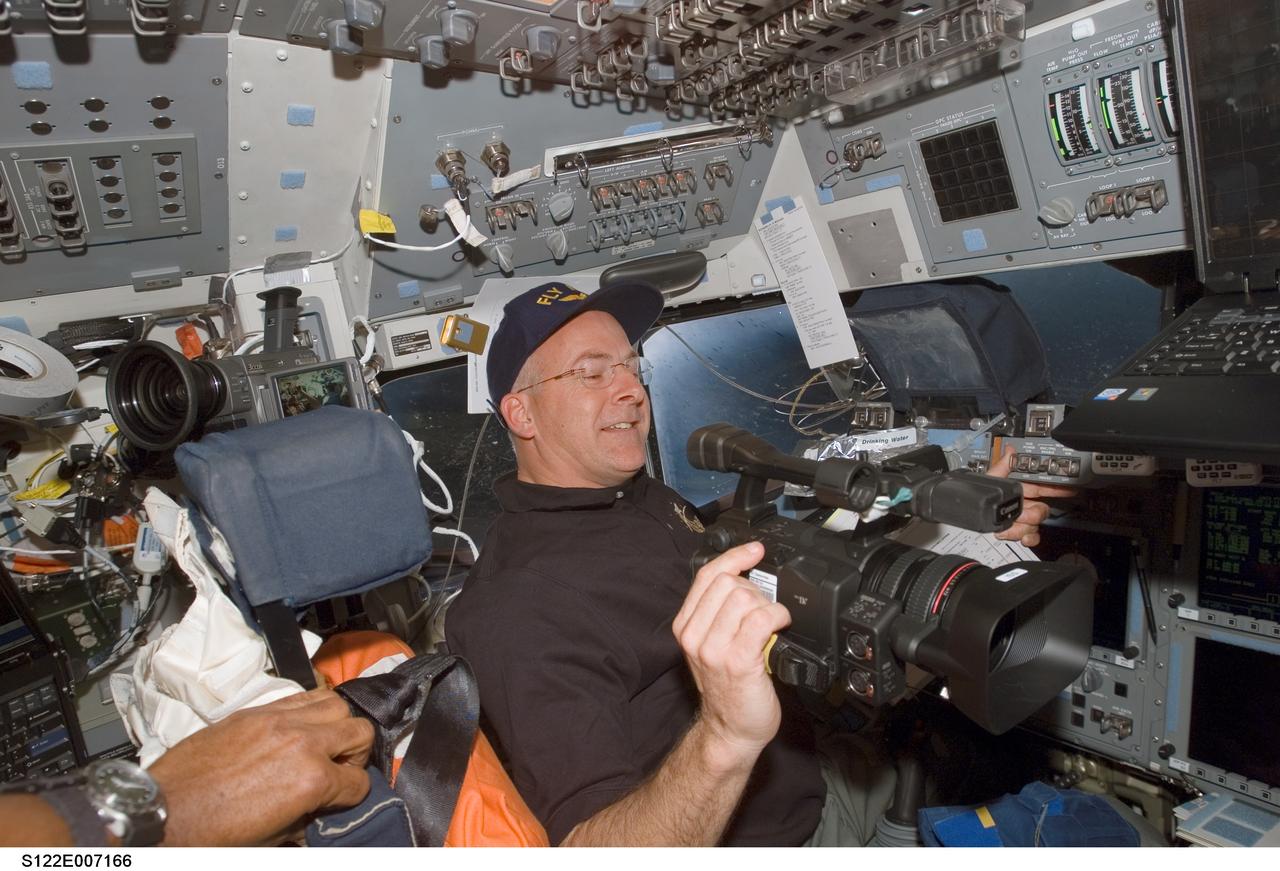 S122-E-007166 (9 Feb. 2008) --- Astronaut Alan Poindexter, STS-122 pilot, prepares to use a High Definition Video (HDV) camera, a Station Detailed Test Objective (SDTO), on the flight deck of Space Shuttle Atlantis during flight day three activities.