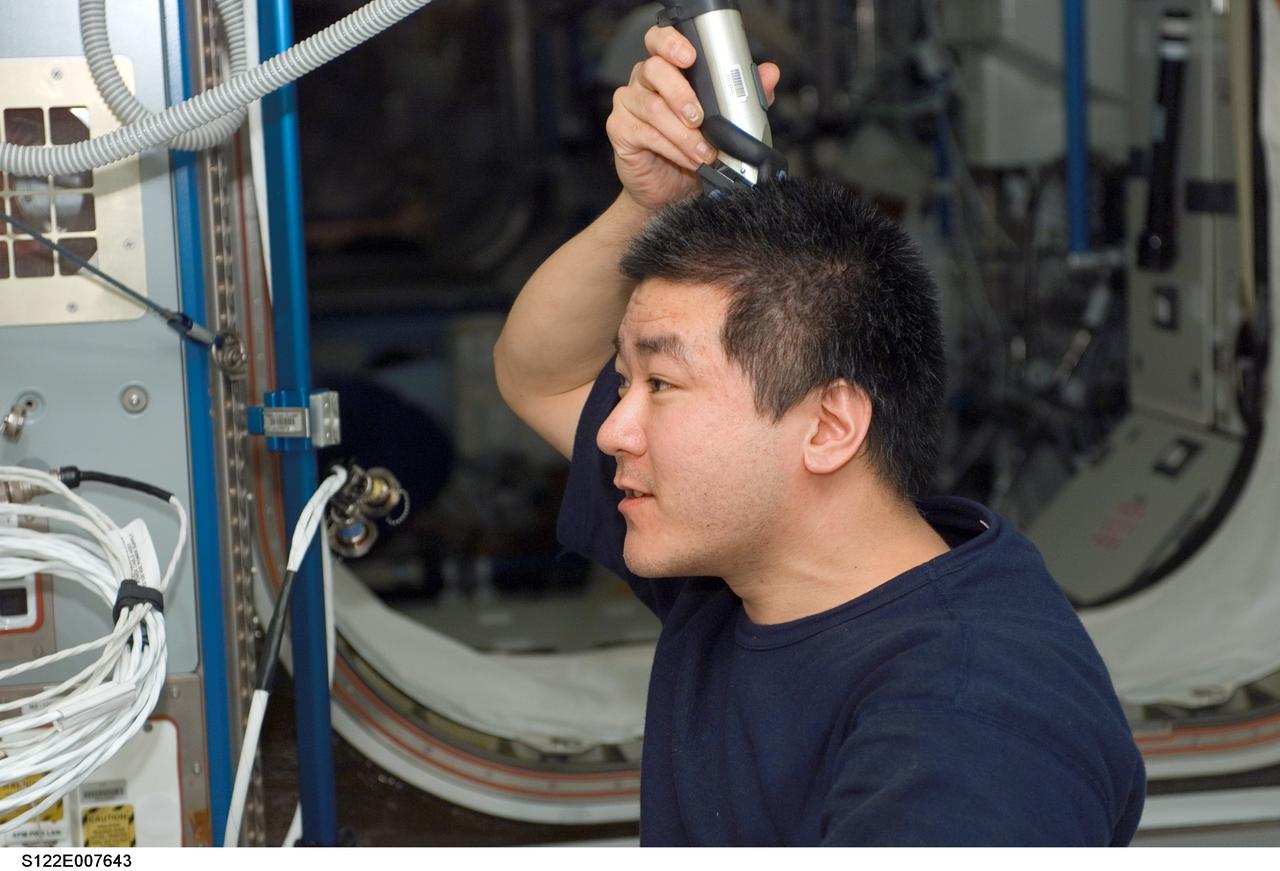 S122-E-007643 (10 Feb. 2008) --- Astronaut Daniel Tani, Expedition 16 flight engineer, trims his hair in the Harmony node of the International Space Station while Space Shuttle Atlantis is docked with the station. Tani used hair clippers fashioned with a vacuum device to garner freshly cut hair.