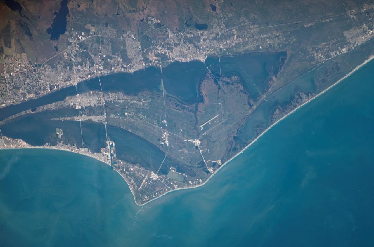 S122-E-007690 (10 Feb. 2008) --- An almost nadir view of the John F. Kennedy Space Center (KSC) was provided by one of STS-122 crewmembers with a digital camera. KSC is the NASA space vehicle launch facility and launch control center (spaceport) on Merritt Island, Brevard County, Florida. The site is near Cape Canaveral, between Miami and Jacksonville. It is 34 miles (55 kilometers) long and around 6 miles (10 kilometers) wide, covering 219 square miles (567 square kilometers). Because much of KSC is a restricted area and only 9 percent of the land is developed, the site also serves as an important wildlife sanctuary; Mosquito Lagoon, Indian River, Merritt Island Wildlife Refuge and Canaveral National Seashore are also features of this area. Pictured just below center is Launch Complex 39, with the roadway leading to the giant Vehicle Assembly Building (VAB), 3 miles (5 kilometers) to the west (above) of the two launch pads. Located 5 miles (8 kilometers) south is the KSC industrial area, where many of the Center's support facilities and the administrative Headquarters Building are located. The Shuttle Landing Facility can be seen northwest of the VAB, in frame center.