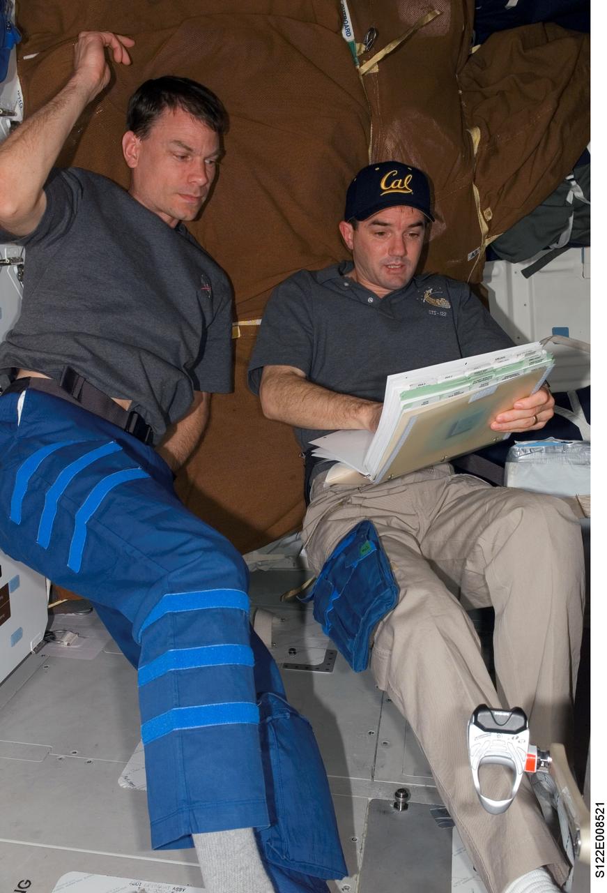 S122-E-008521 (14 Feb. 2008) --- Astronauts Stanley Love (left) and Rex Walheim, both STS-122 mission specialists, look over checklists on the middeck of Space Shuttle Atlantis while docked with the International Space Station.