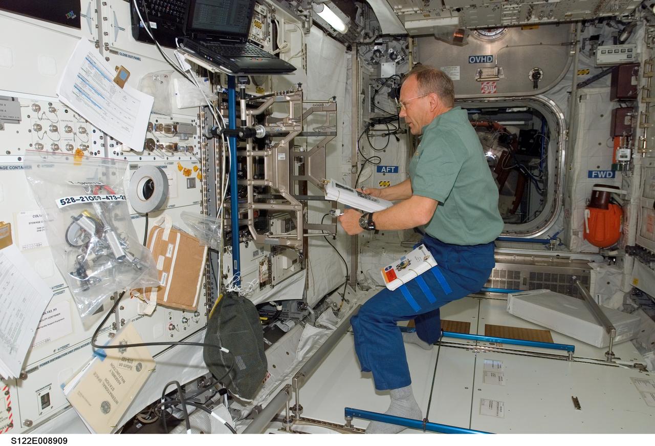 S122-E-008909 (15 Feb. 2008) --- European Space Agency astronaut Hans Schlegel, STS-122 mission specialist, continues work aimed toward readying the agency's new Columbus laboratory for duty aboard the International Space Station. A pictorial guidebook assists the astronaut in installing the lab's experiment racks.