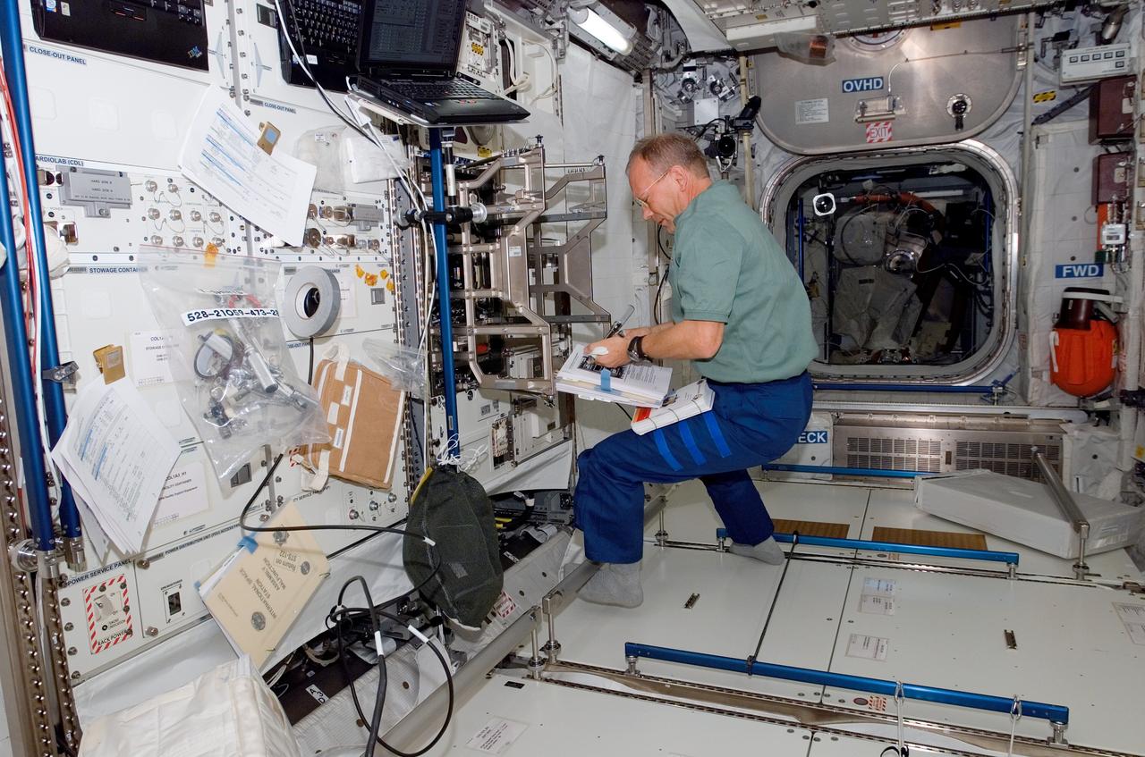 S122-E-008911 (15 Feb. 2008) --- European Space Agency astronaut Hans Schlegel, STS-122 mission specialist, continues work aimed toward readying the agency's new Columbus laboratory for duty aboard the International Space Station. A pictorial guidebook assists the astronaut in installing the lab's experiment racks.