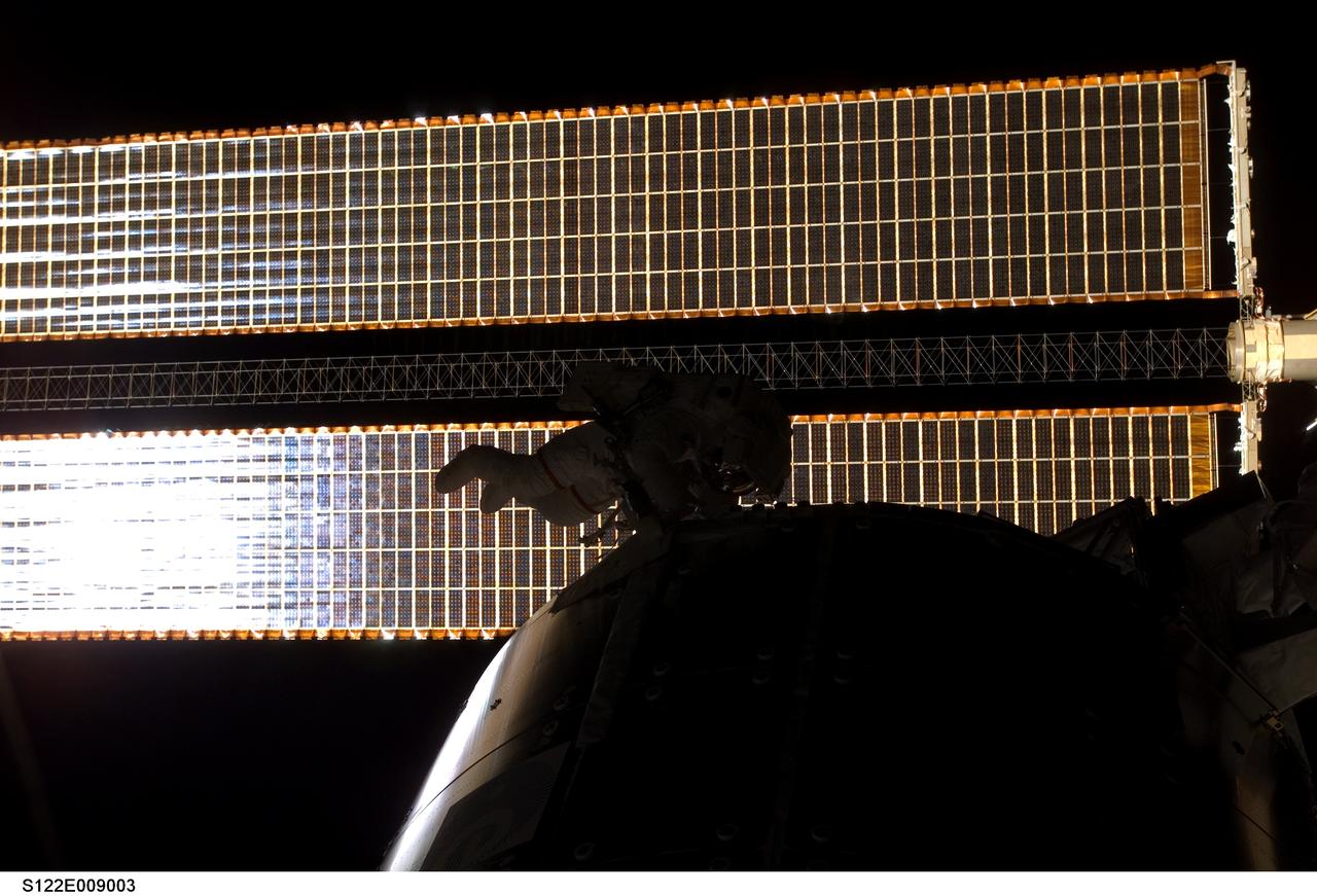 S122-E-009003 (15 Feb. 2008) --- Silhouetted against the starboard solar array of the International Space Station, astronaut Rex Walheim, STS-122 mission specialist, works to install handrails and worksite interface fixtures on the Columbus laboratory during the mission's third session of extravehicular activity (EVA) while Space Shuttle Atlantis is docked with the station.
