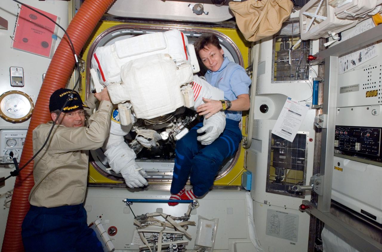 S122-E-009094 (15 Feb. 2008) --- Commanders of the STS-122 Atlantis crew and the International Space Station's expedition, respectively, astronauts Steve Frick and Peggy Whitson, assist astronaut Rex Walheim as he ingresses the station following the third and final extravehicular activity during a week in which the Atlantis was docked to the orbital outpost. Astronaut Stanley Love (out of frame), mission specialist, shared this extravehicular activity with Walheim.